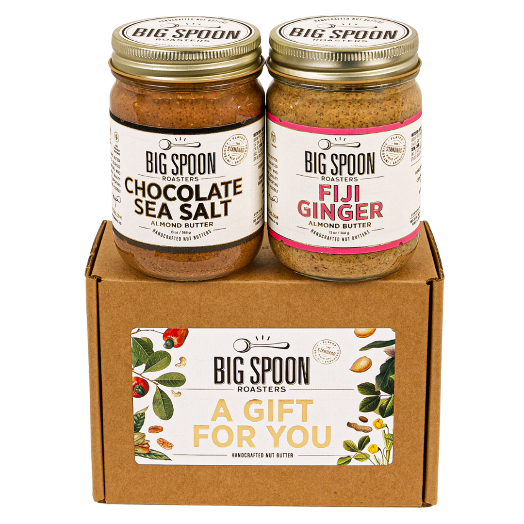 Jar of Chocolate Sea Salt Almond Butter next to a jar of Fiji Ginger Almond Butter on top of a gift for you box