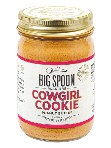 13oz glass jar of Cowgirl Cookie Peanut Butter with deep pink lettering and border on the label