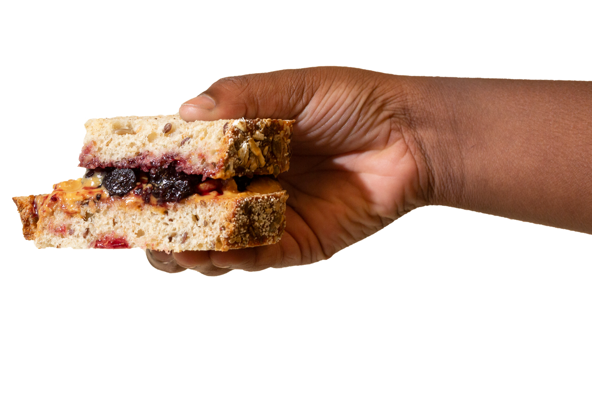 hand holding a peanut butter and jelly sandwich