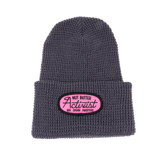 Gray beanie with a pink patch embroidered with the words NUT BUTTER ACTIVIST | BIG SPOON ROASTERS