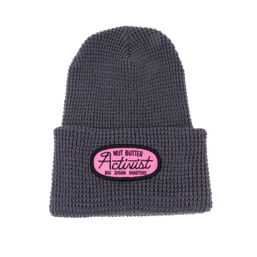 Gray beanie with a pink patch embroidered with the words NUT BUTTER ACTIVIST | BIG SPOON ROASTERS