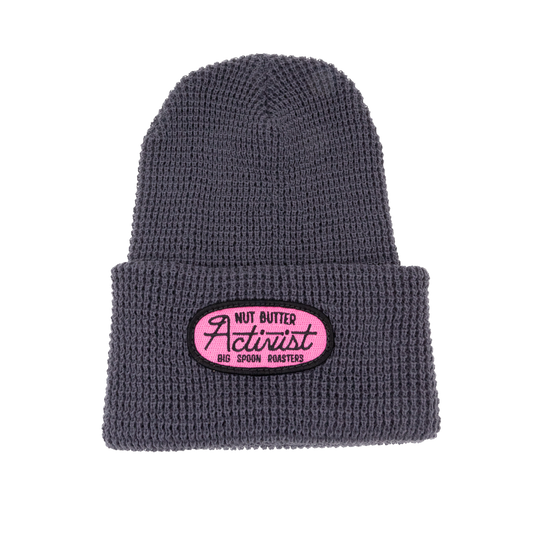 Gray beanie with a pink patch embroidered with the words NUT BUTTER ACTIVIST | BIG SPOON ROASTERS