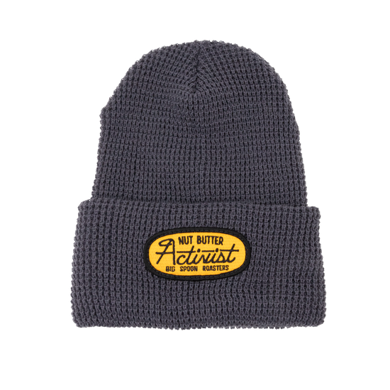 Gray beanie with a yellow patch embroidered with the words NUT BUTTER ACTIVIST | BIG SPOON ROASTERS