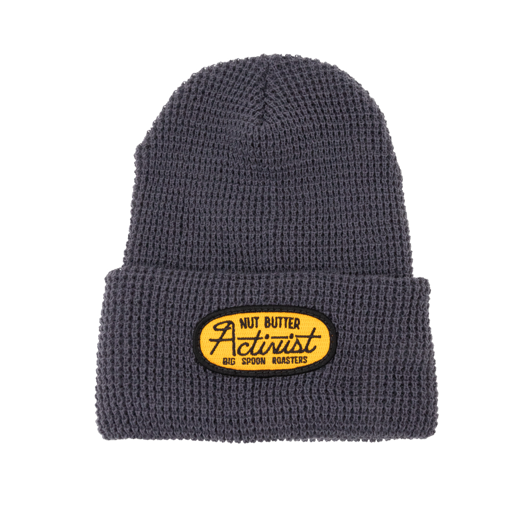 Gray beanie with a yellow patch embroidered with the words NUT BUTTER ACTIVIST | BIG SPOON ROASTERS