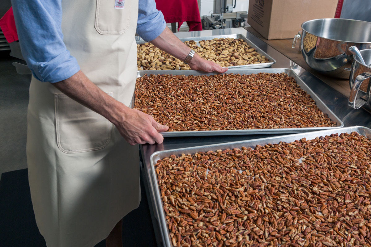 hand holding a sheet of pecans prior to roasting them