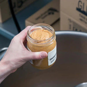 Nut Butter jar being held over a stainless steel bowl.