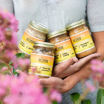 Flowers in the front of someone holding community blend jars in their arms. 