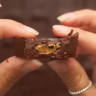 close up of hands holding bitten peanut butter cup