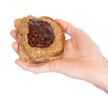 A hand holding a piece of toast with Almond Butter and jam