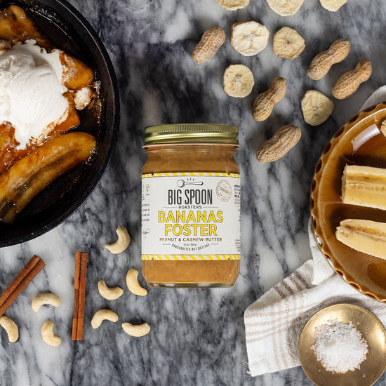 Jar of Bananas Foster Peanut & Cashew Butter styled with bananas and nuts