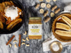 Jar of Bananas Foster Peanut & Cashew Butter styled with bananas and nuts