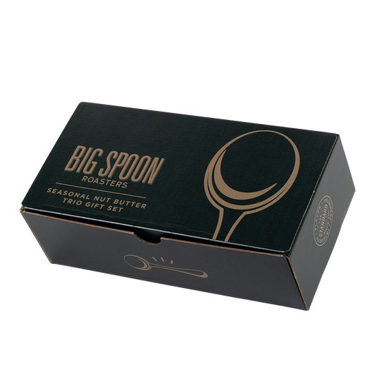 A dark green rectangular gift box for Big Spoon Roasters Seasonal Nut Butter Trio Gift Set, featuring gold foil text and spoon illustrations, photographed on a clean white background.