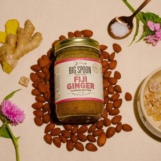 jar of Fiji Ginger Almond Butter surrounded by almonds, ginger, candied ginger, and sea salt