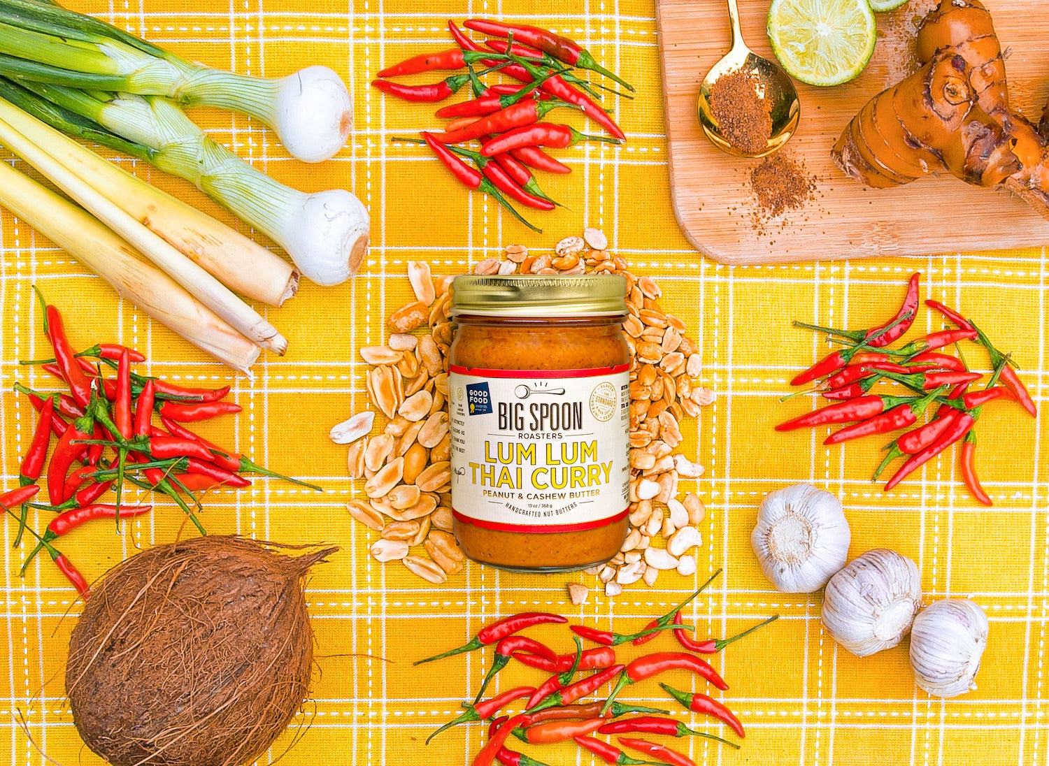 Lum Lum Thai Curry Peanut & Cashew Butter surrounded by ingredients on a yellow backdrop