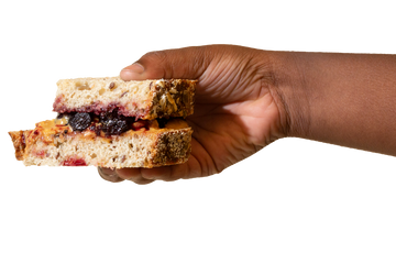 A hand holds a PB&J sandwich