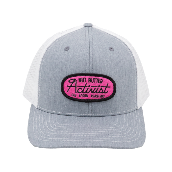 Light gray trucker hat with pink patch reading "NUT BUTTER ACTIVIST BIG SPOON ROASTERS"