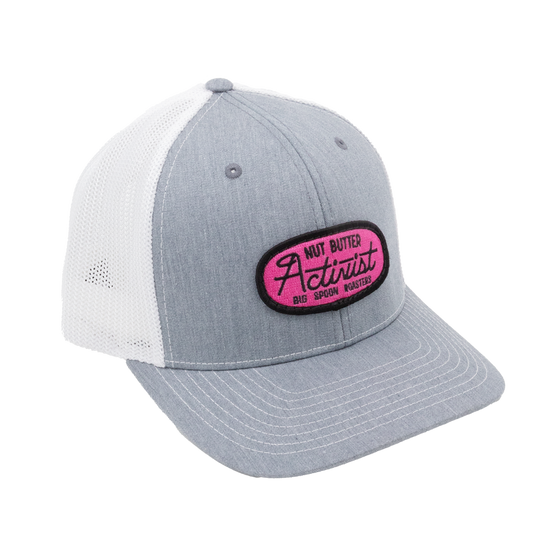 Light gray trucker hat with pink patch reading "NUT BUTTER ACTIVIST BIG SPOON ROASTERS"